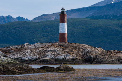 Lighthouse by sea against mountain