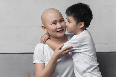 Portrait of father and son against wall