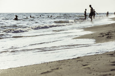 People on beach by sea against sky