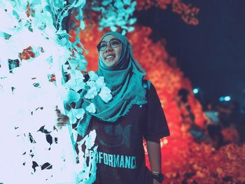 Full length of woman standing against illuminated wall