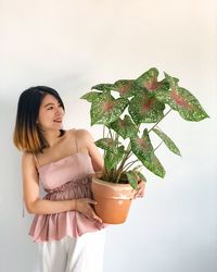 Young woman looking away while standing on potted plant