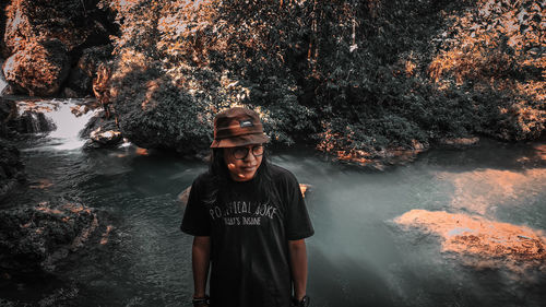 Portrait of young man wearing sunglasses standing against trees