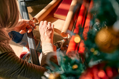 Blond woman wrapping presents in recycled card and decorated it with dried oranges and fir branches.