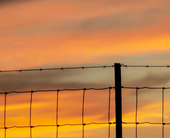 Fence against sky at sunset