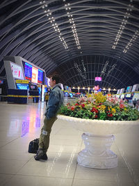 Side view of young man standing by illuminated text on tiled floor