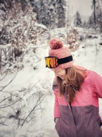 Rear view of woman playing in snow wearing ski clothing