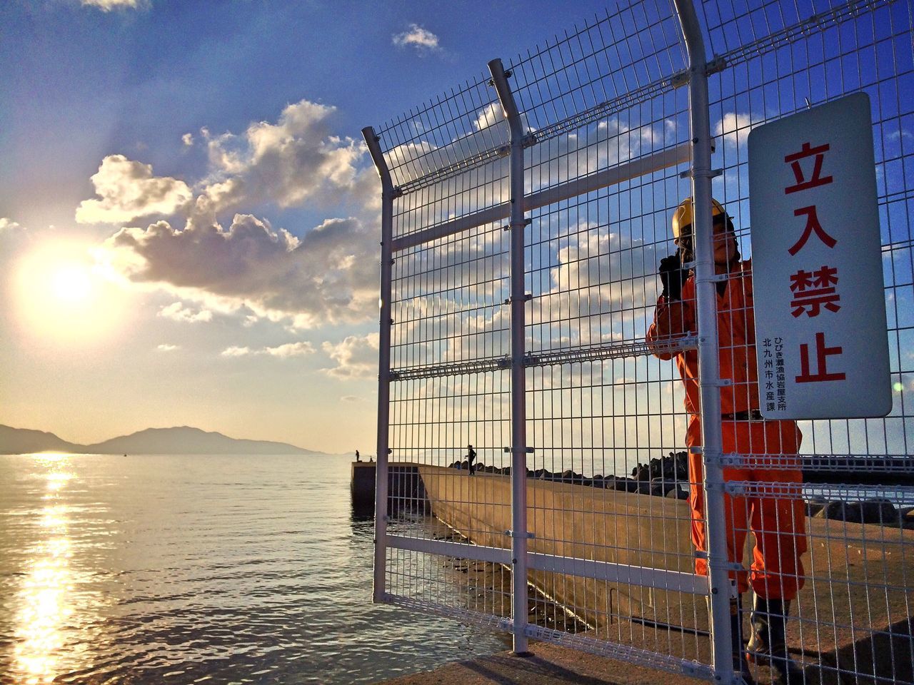 building exterior, architecture, built structure, sky, water, western script, text, transportation, city, reflection, sunlight, sea, communication, cloud - sky, mode of transport, sunset, nautical vessel, railing, outdoors, cloud