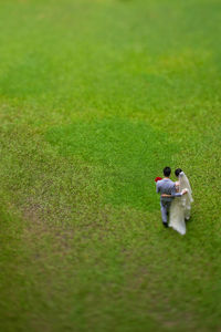 High angle view of newly wed couple walking on grassy field