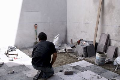 Rear view of man working against wall