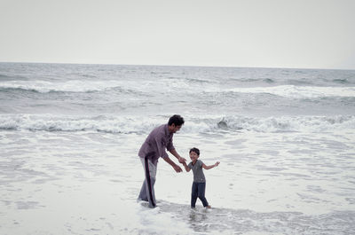 Man with cheerful daughter enjoying in sea against clear sky