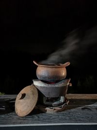 Close-up of clay pot on table against sky at night