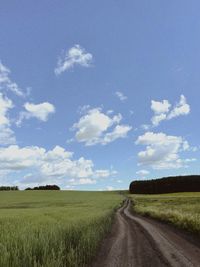 Road amidst field against sky