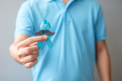 Midsection of man holding umbrella against blue background