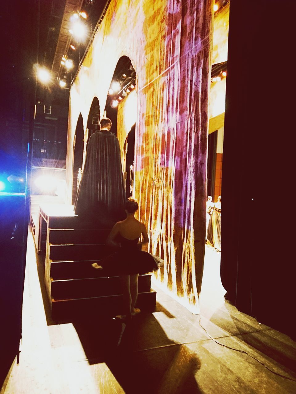 REAR VIEW OF PEOPLE STANDING AT ILLUMINATED ENTRANCE OF BUILDING