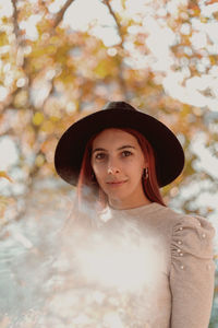 Portrait of beautiful young woman standing against plants