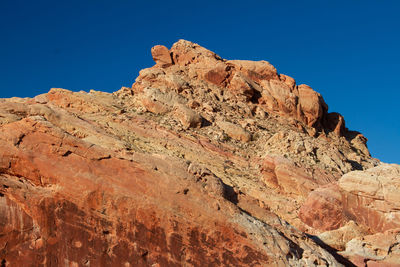 Low angle view of rock formation against clear blue sky