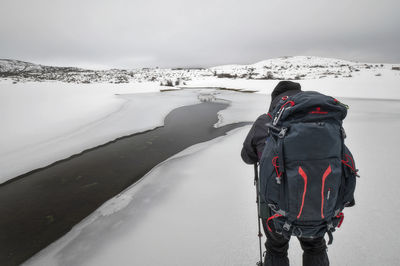 Rear view of people on snow covered mountain against sky