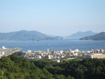 Scenic view of city by sea against clear sky