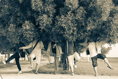 Low section of friends dancing amidst trees at park