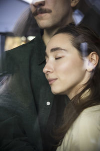 Woman with eyes closed leaning on boyfriend at home