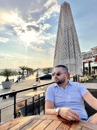 Low angle view of man sitting on roof against sky