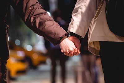Midsection of couple holding hands in city