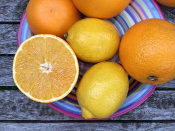 Close-up of halved and whole oranges in plate