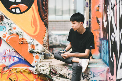 Woman sitting on graffiti wall