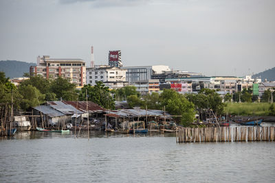 Buildings by river against sky