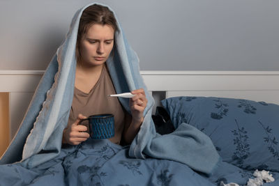 Sick woman checking temperature at home