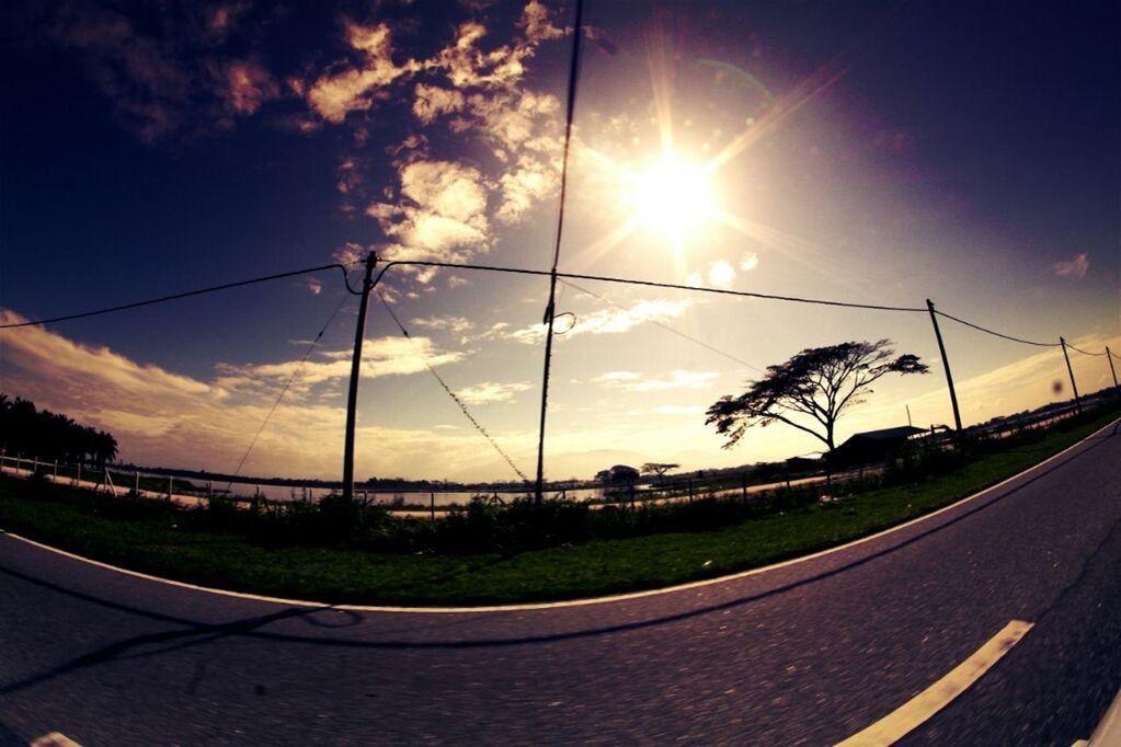 road, sky, transportation, sun, cloud - sky, sunset, road marking, sunlight, the way forward, street, cloud, sunbeam, car, diminishing perspective, cloudy, nature, tree, country road, scenics, tranquility