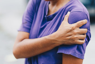 Midsection of woman standing against purple wall