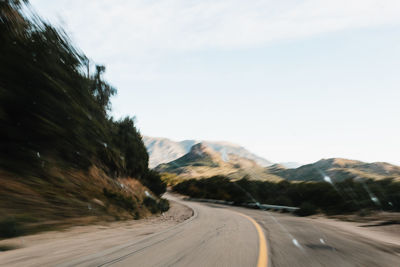 Empty road by mountain against sky