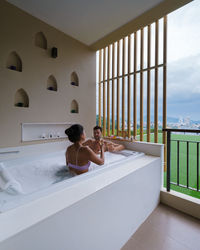 Rear view of woman swimming in bathroom