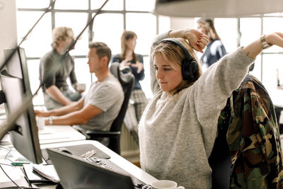 Female entrepreneur stretching while looking at computer in office