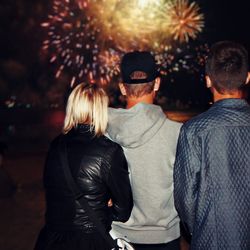 Rear view of people standing against fireworks at night