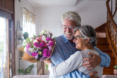 Smiling couple holding bouquet at home