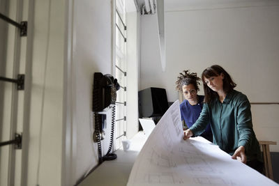 Female architects with blueprint at table in office