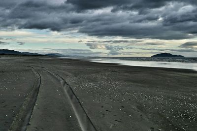 Scenic view of beach against cloudy sky