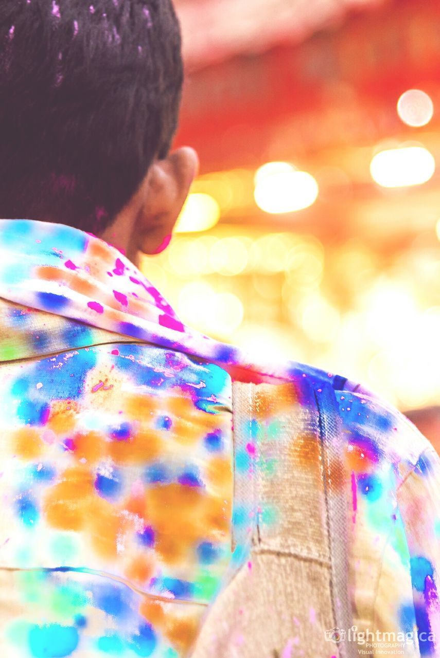 REAR VIEW OF MAN WITH MULTI COLORED LIGHT