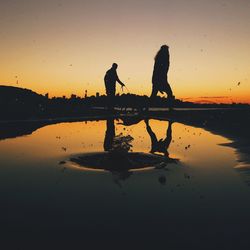 Reflection of silhouette trees in water at sunset