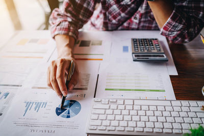 Midsection of businessman doing paperwork at desk in office