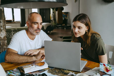 Male and female food stylists watching laptop at table in studio