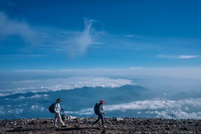 Men standing on mountain against sky