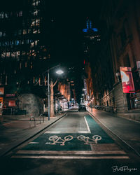 Illuminated street amidst buildings in city at night