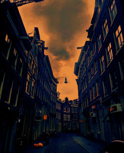 Street amidst buildings against sky at sunset