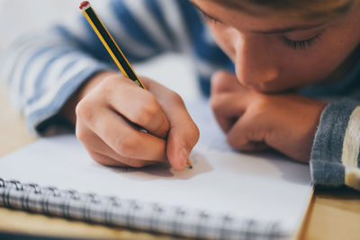 Close-up of boy writing in notebook