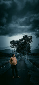 Rear view of man standing by road against sky