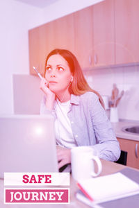 Portrait of young woman using phone while sitting on table