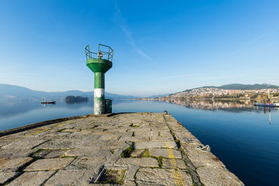Tower by sea against blue sky